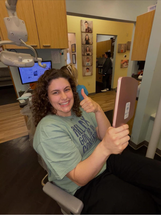 Girl sitting in chair smiling with thumbs-up